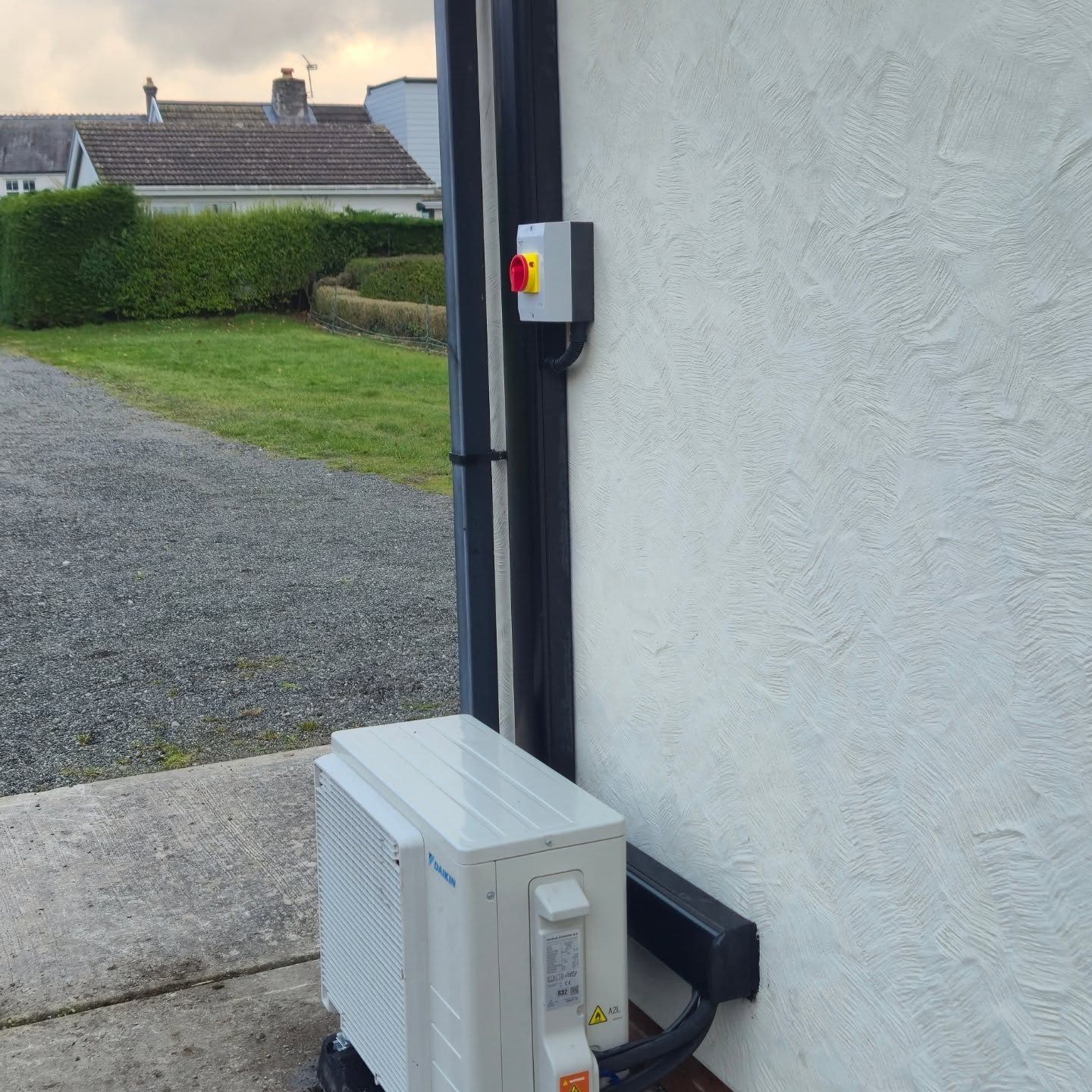Daikin air-to-air heat pump outdoor unit installed against a rendered wall